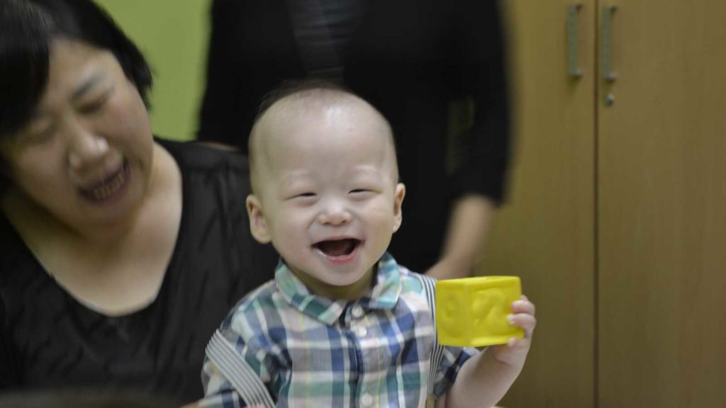 Korean toddler laughing with toy block