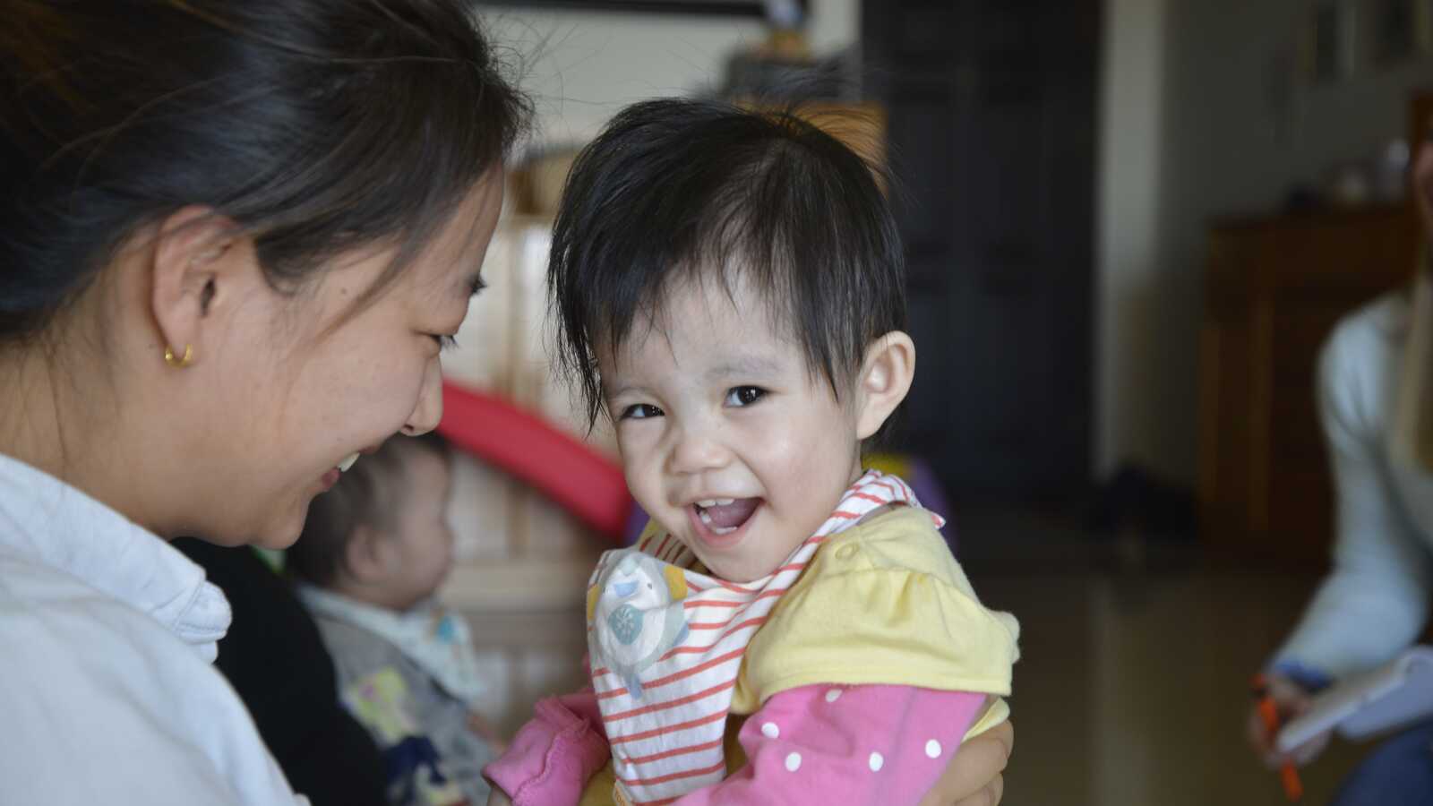 Happy Chinese baby girl with caretaker