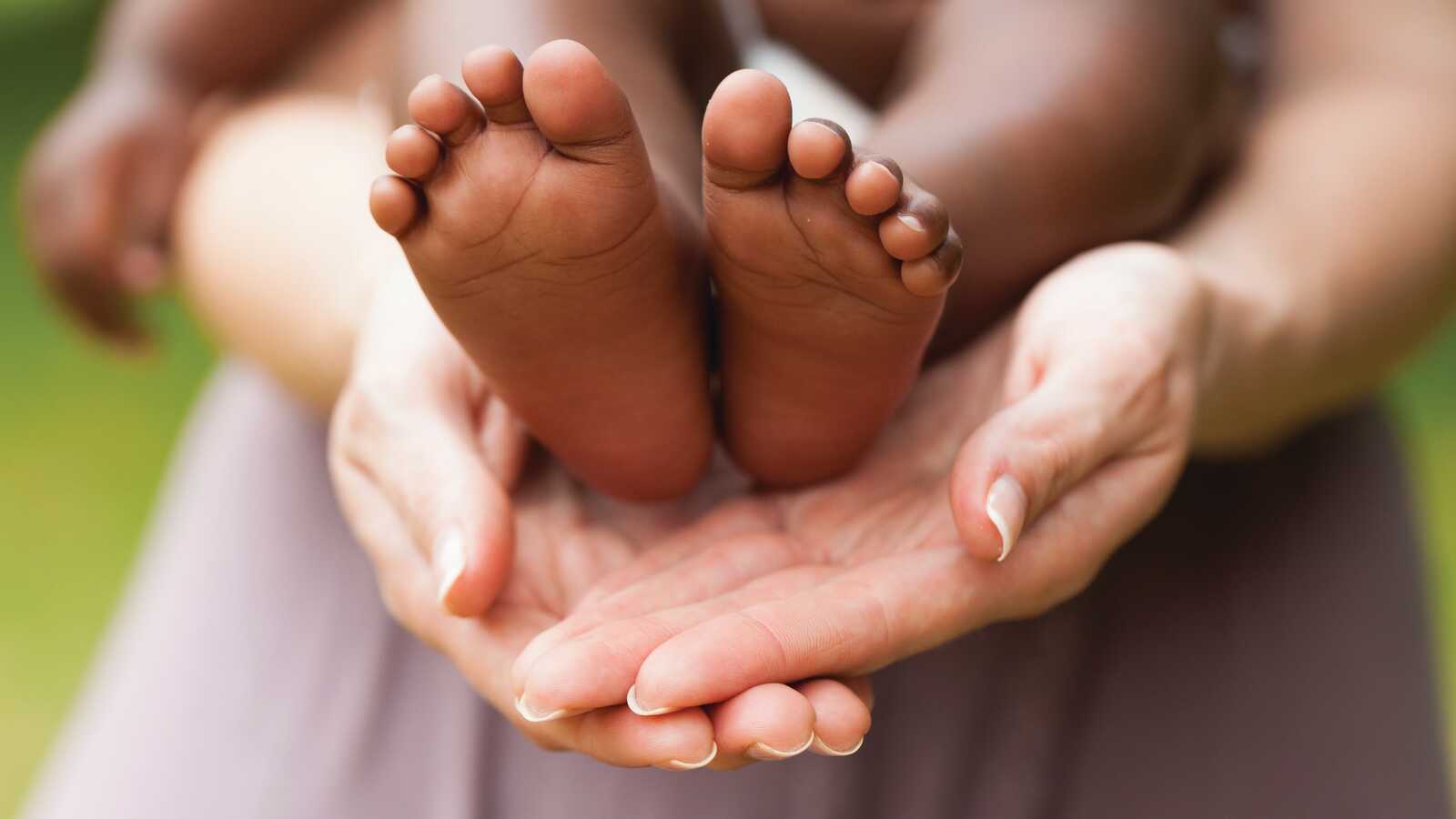 woman holing babies feet