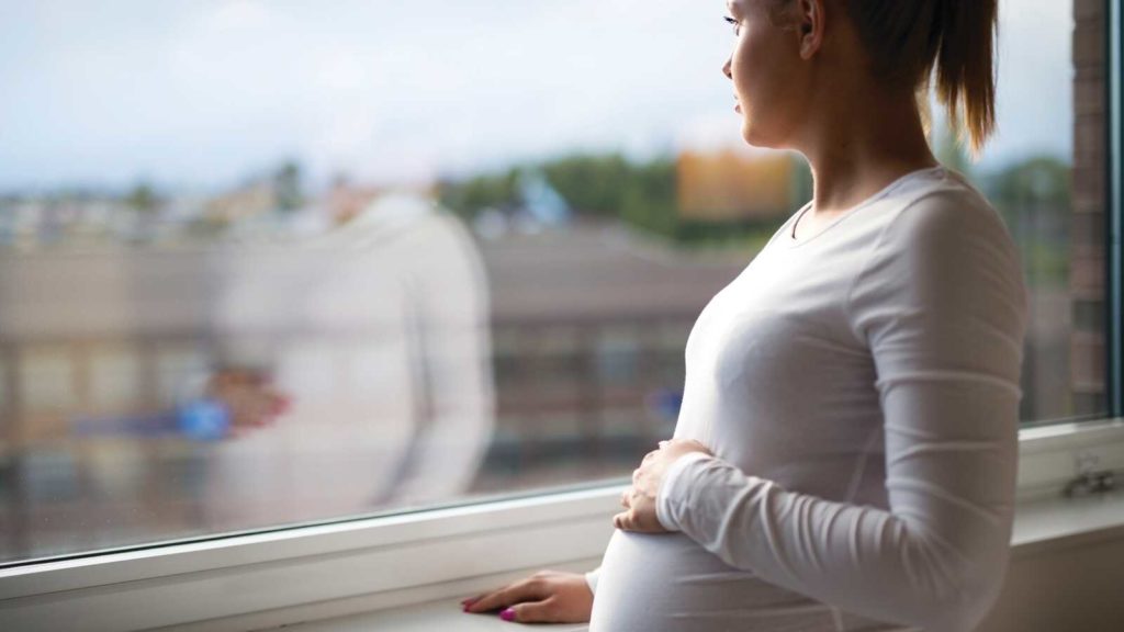 Pregnant woman stares out window