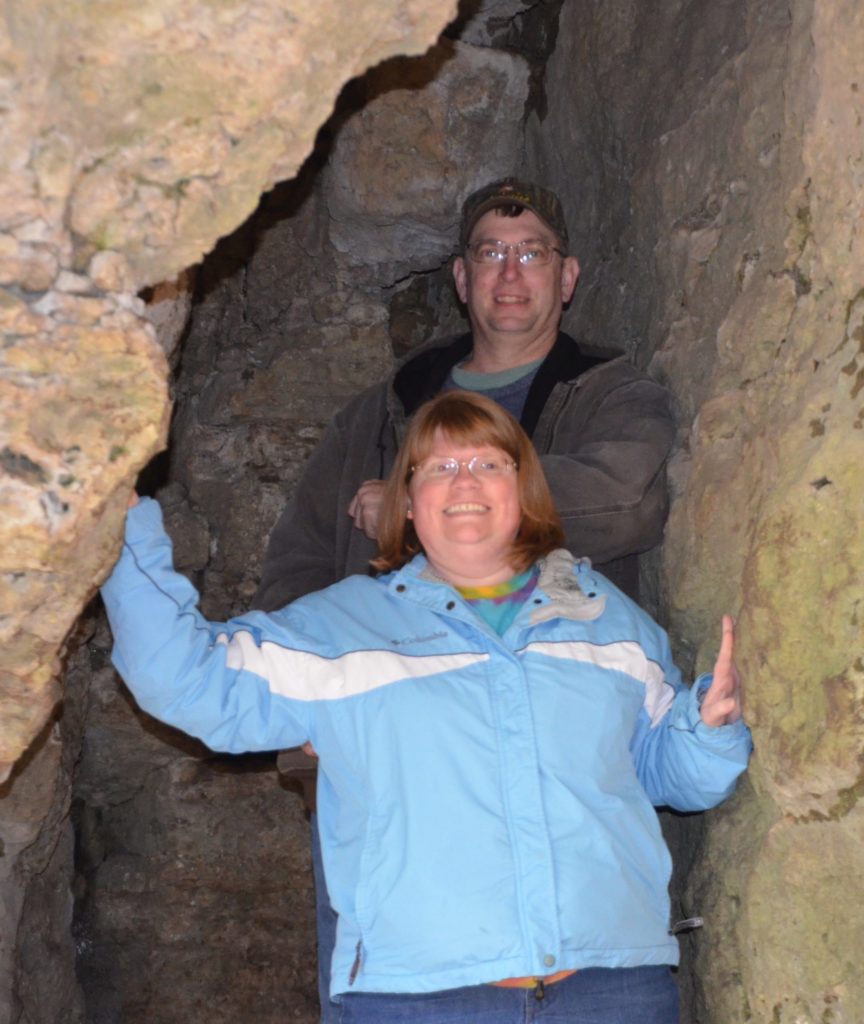 man and woman climbing through cave tunnel