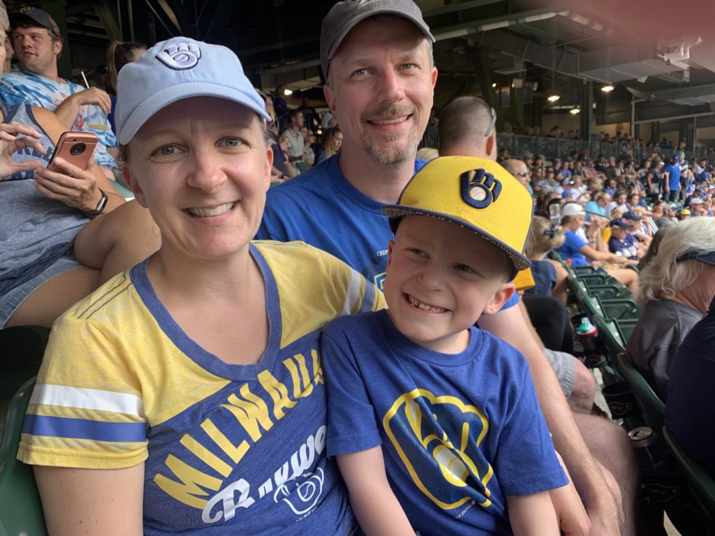smiling man woman and son in blue and yellow clothing in the stands of a sports game