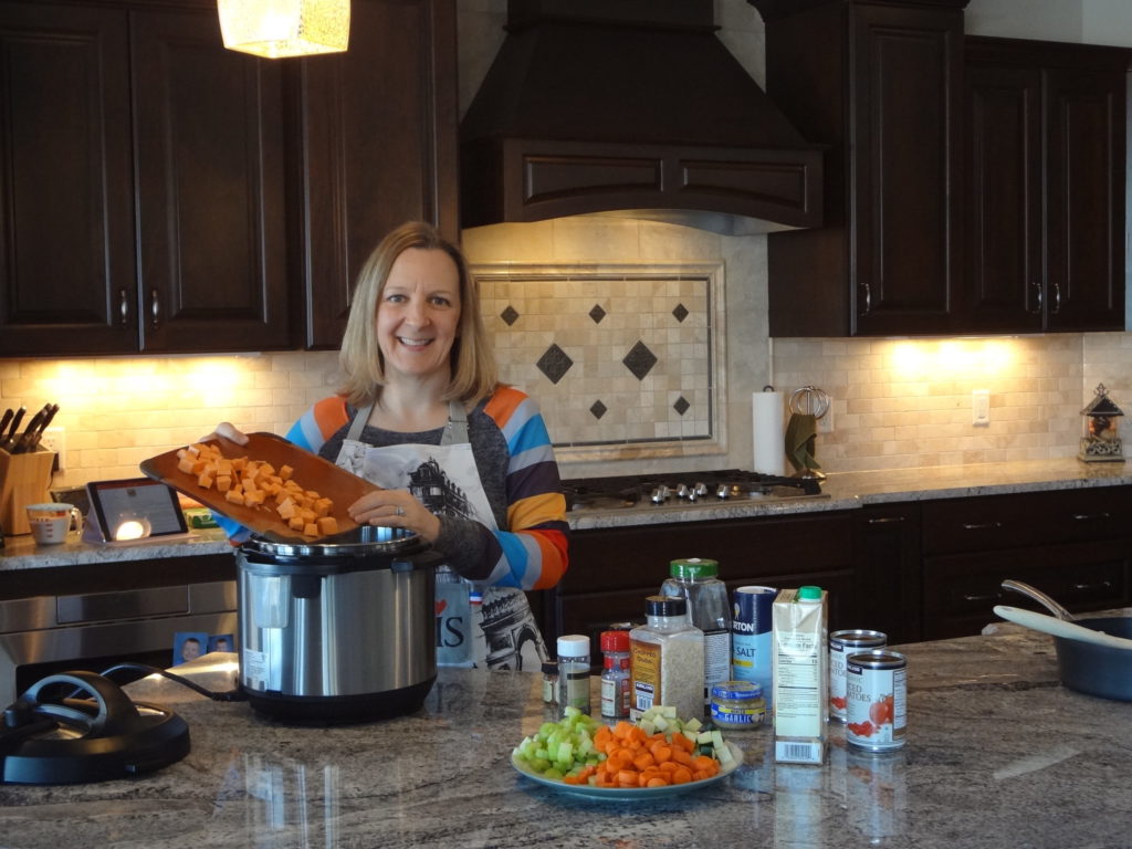 smiling woman pouring chopped carrots into an instant pot