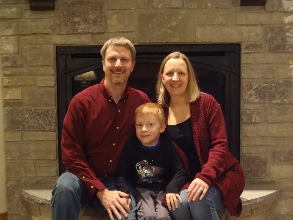 smiling man woman and boy sitting in front of fireplace