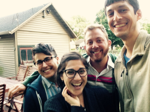 four smiling people with their arms around each other