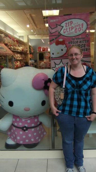 woman posing next to stuffed statue of white cat
