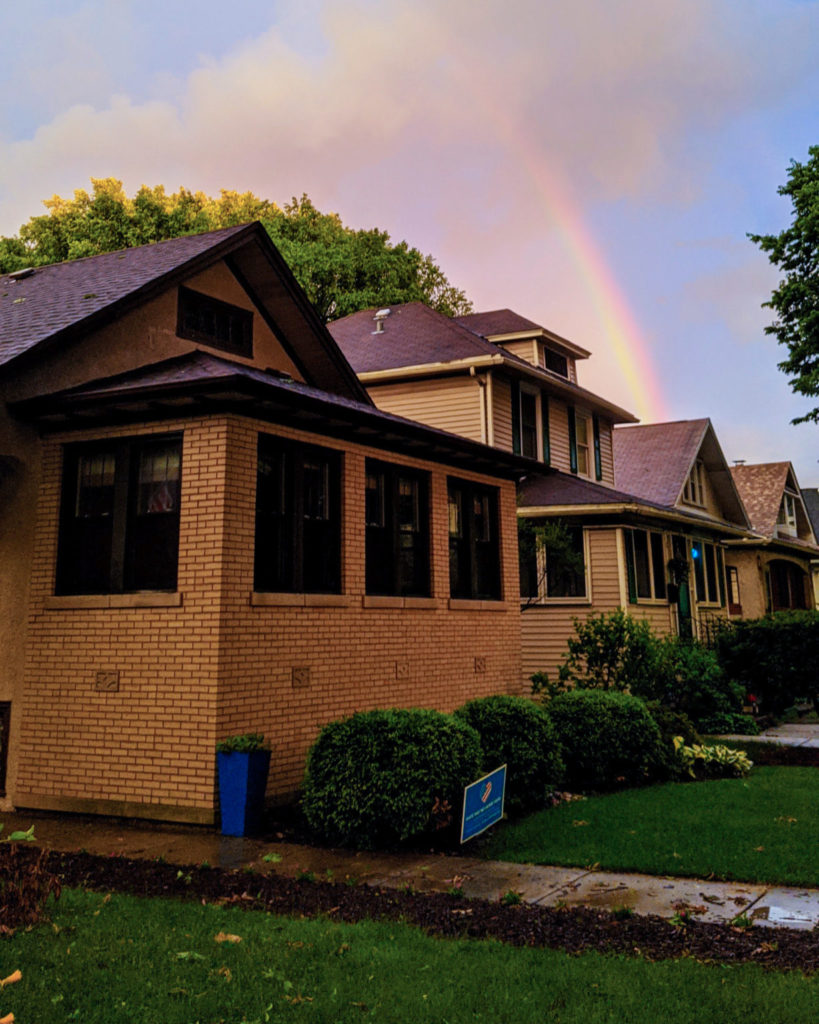 brown brick house with rainbow in the background