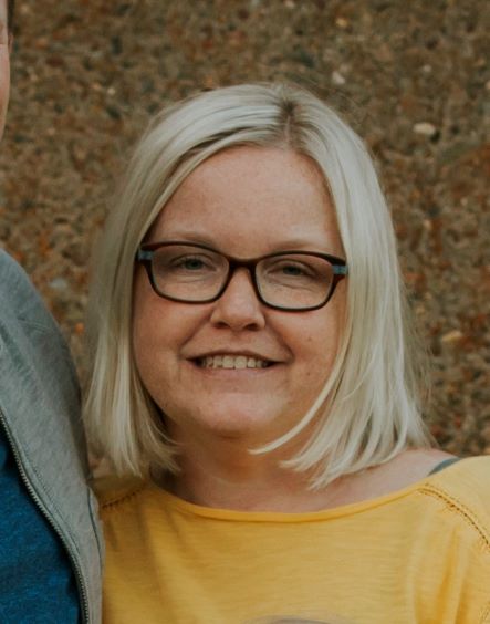 smiling woman with short blonde hair and glasses