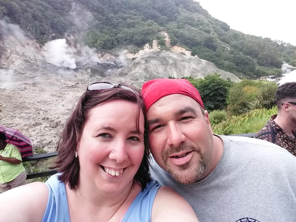 selfie of smiling man and woman in front of rocky hill