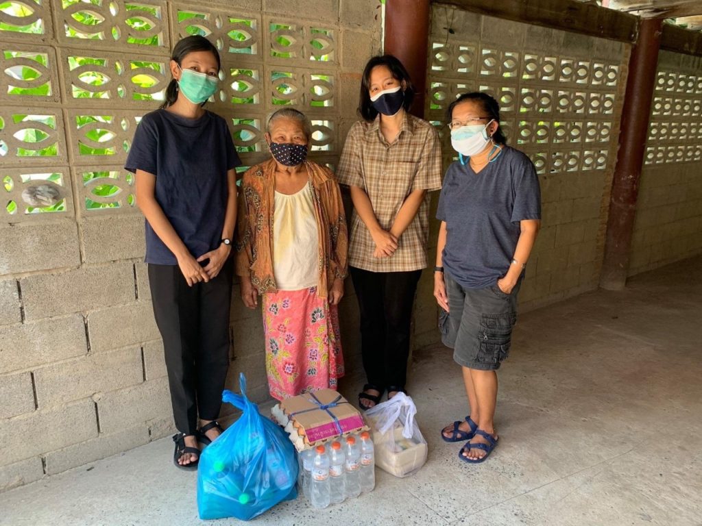 four people wearing masks standing in front of food supplies