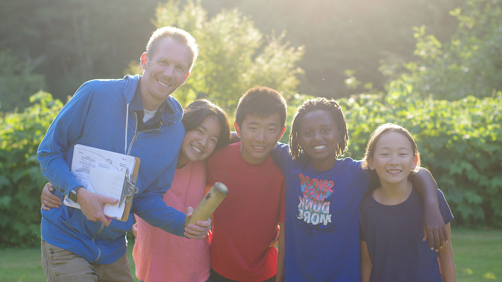 adoptive father with arms around four older adopted children