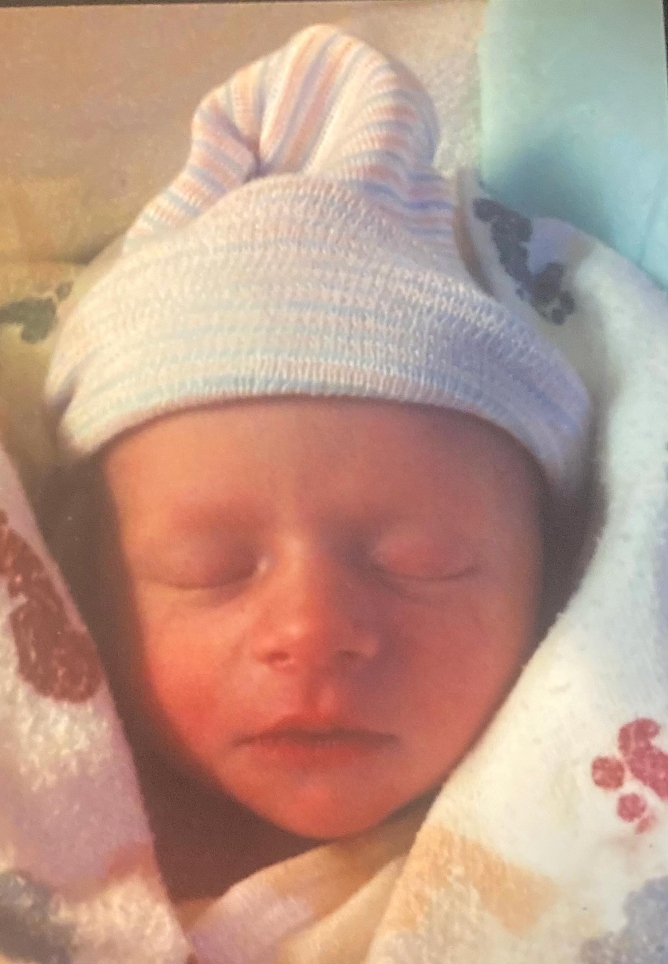 newborn baby wrapped in blanket wearing hat