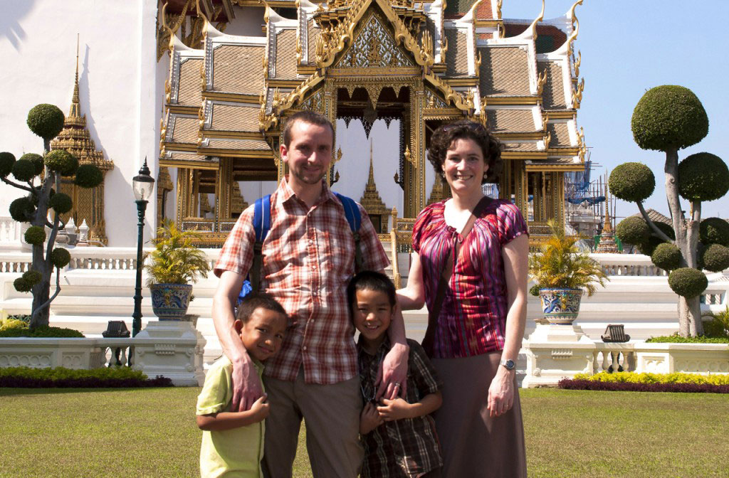 Adoptive parents and two sons in front of Thai temple