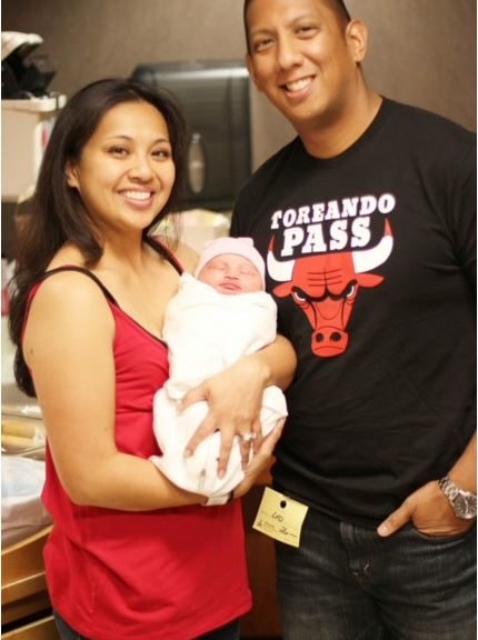 woman holding newborn baby standing next to man