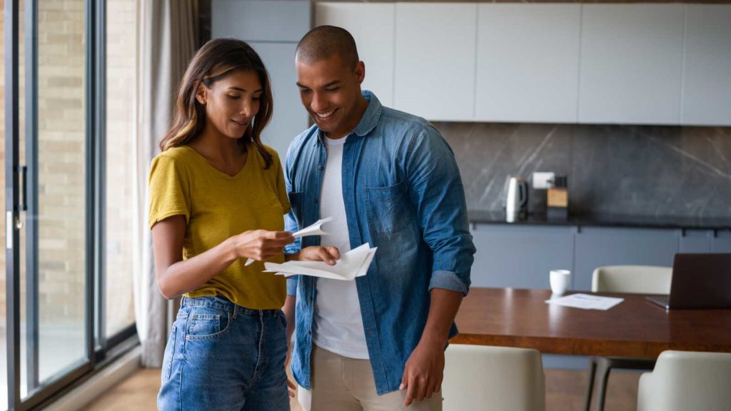 happy couple standing in modern home reviewing financial papers