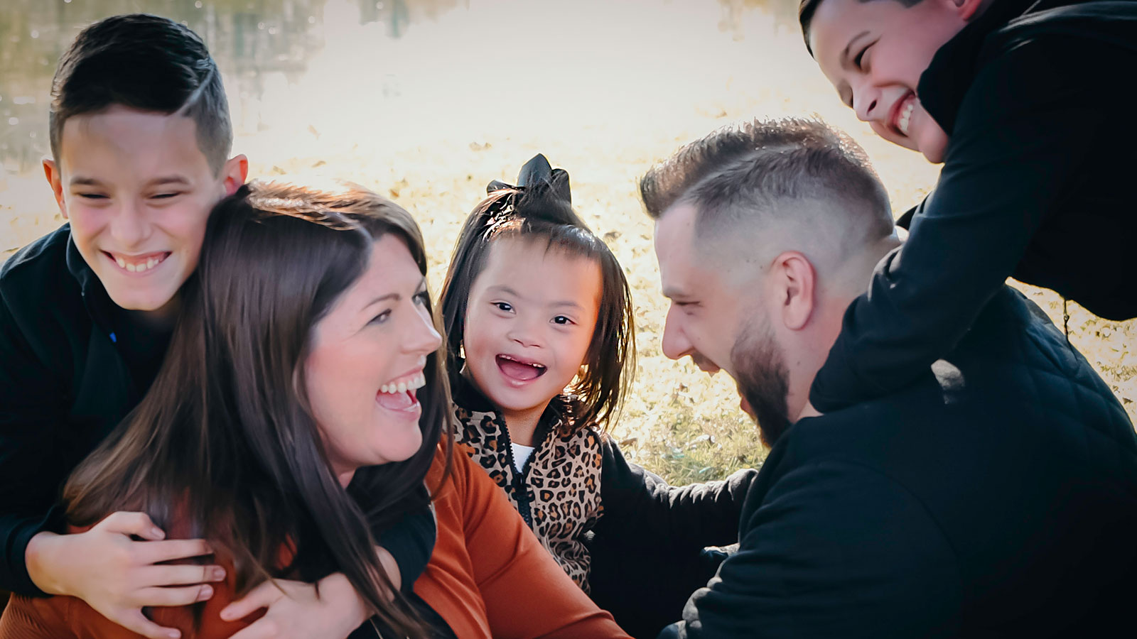 smiling girl with down syndrome adopted from China surrounded by smiling adoptive parents and two brothers