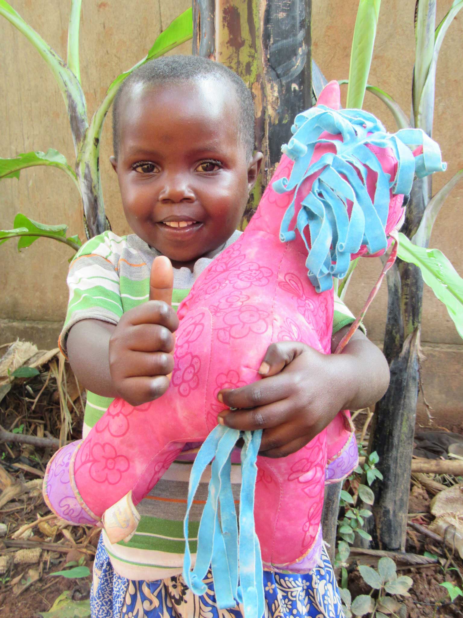 Girl holding pink toy with thumbs up