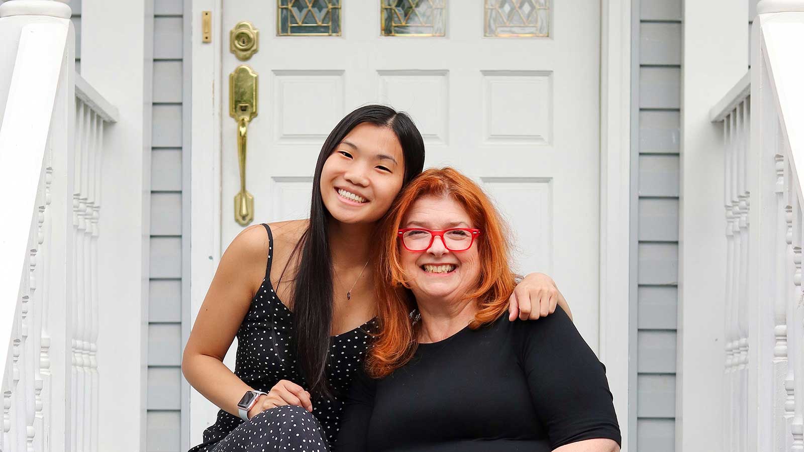 asian daughter with caucasian mother smiling on stairs