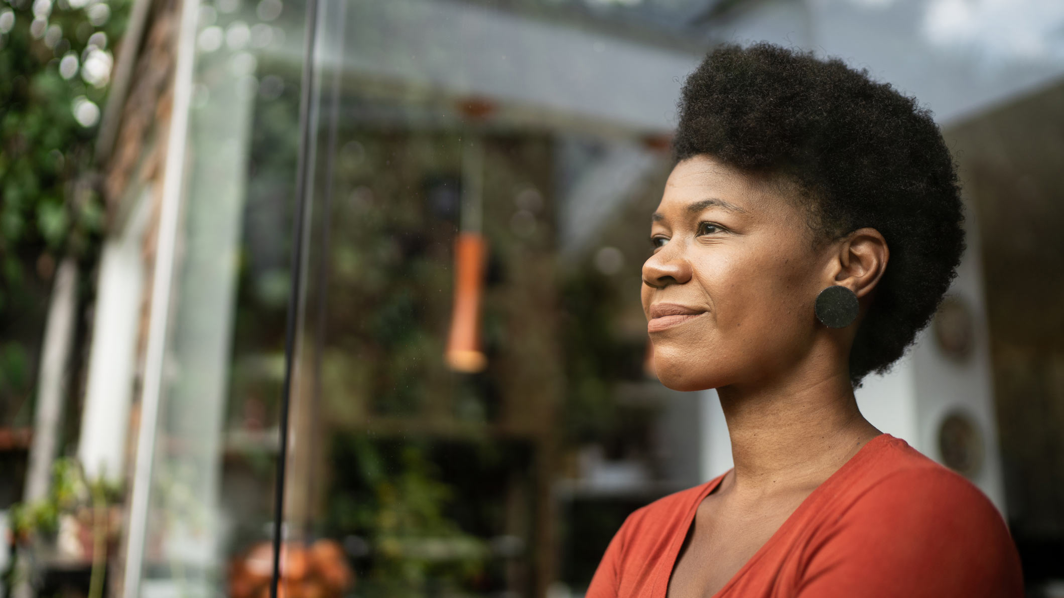 black woman looking into the distance wearing a red shirt