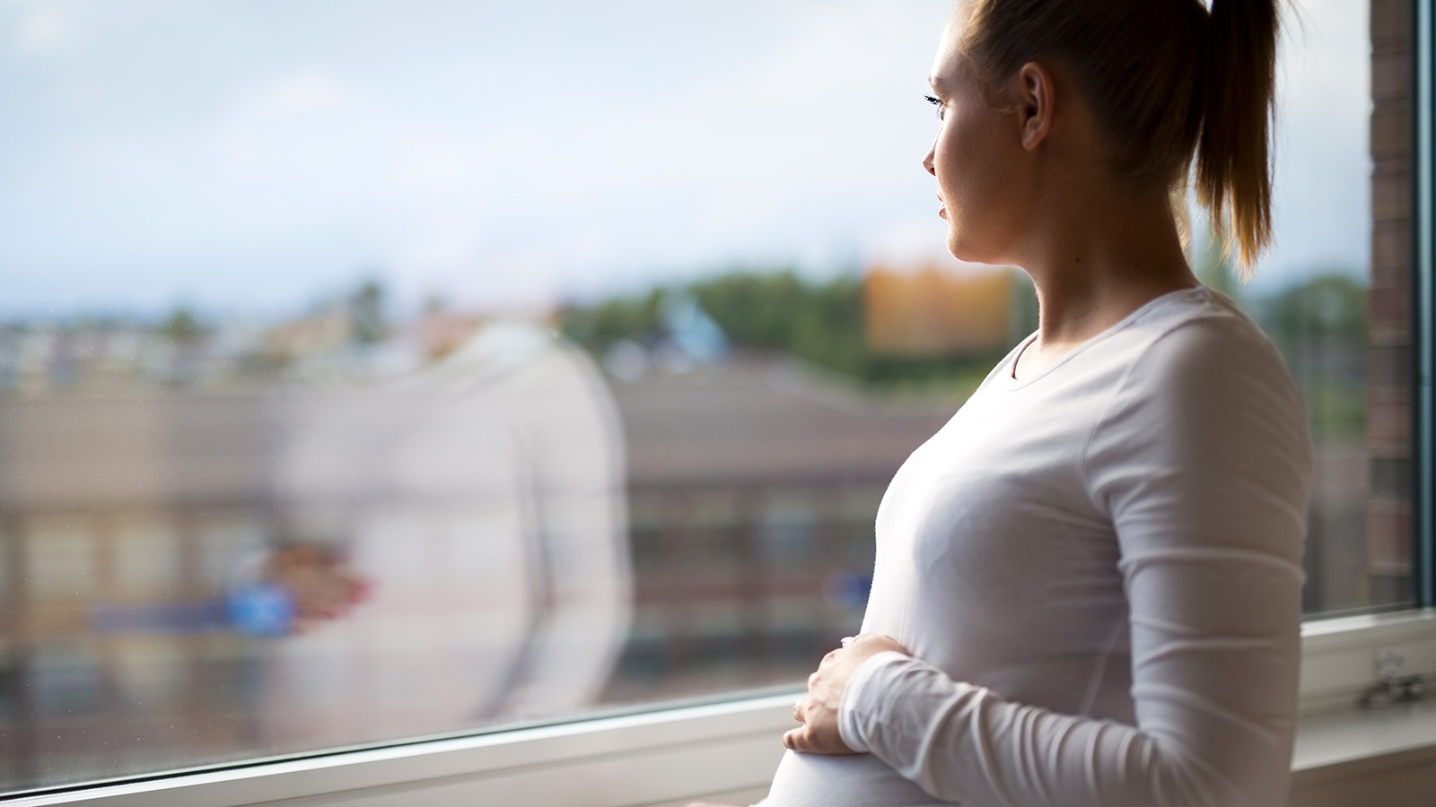 thoughtful pregnant woman looking out the window