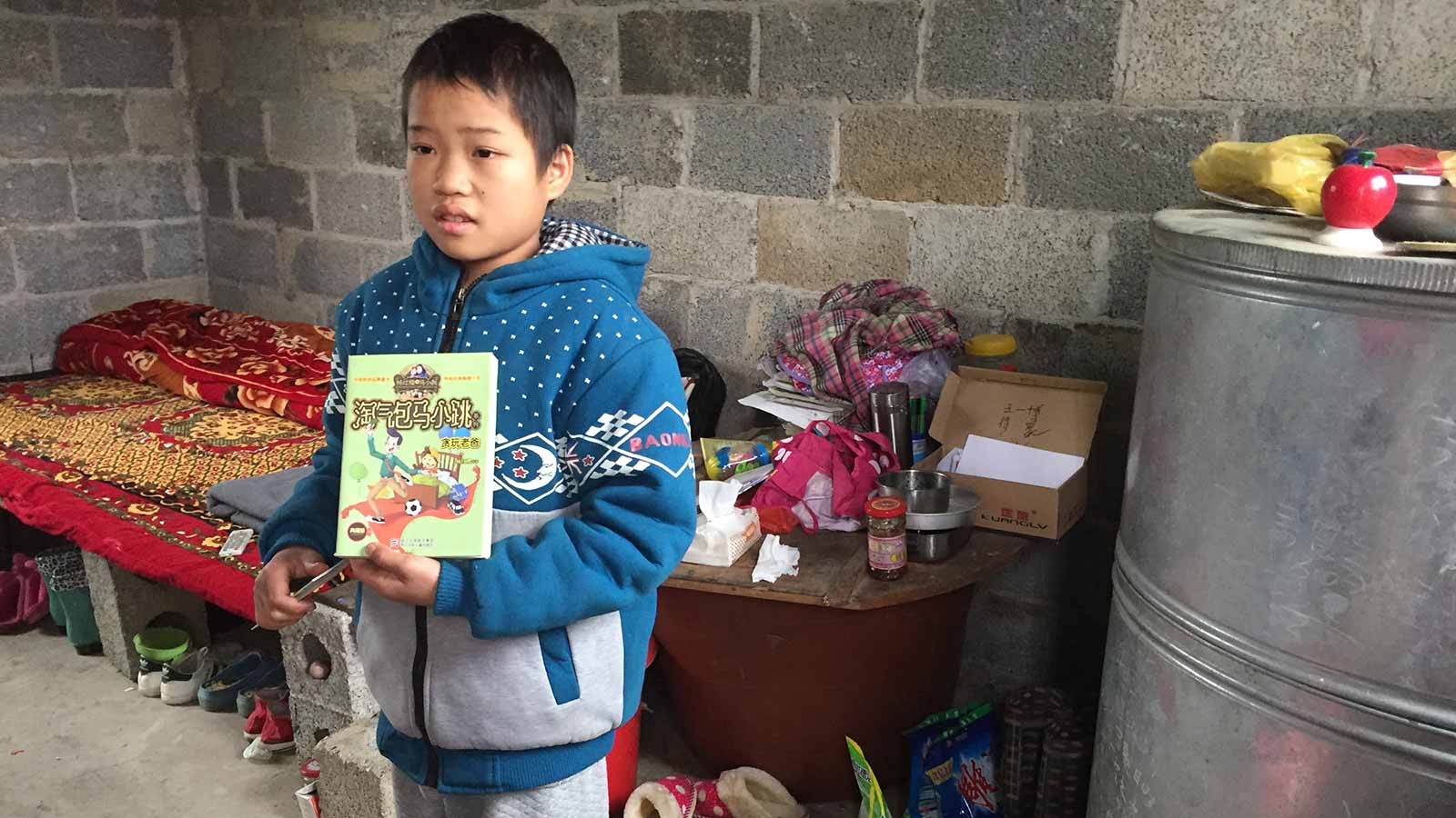 boy holding book in a poor dwelling in China