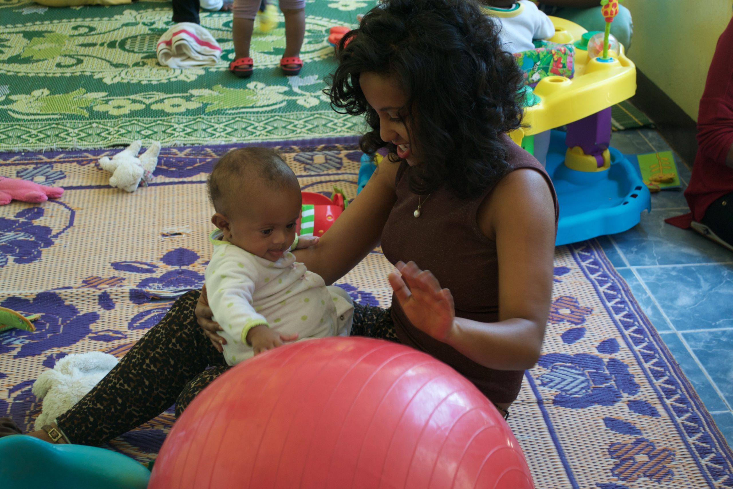 mom playing with her baby and a red ball