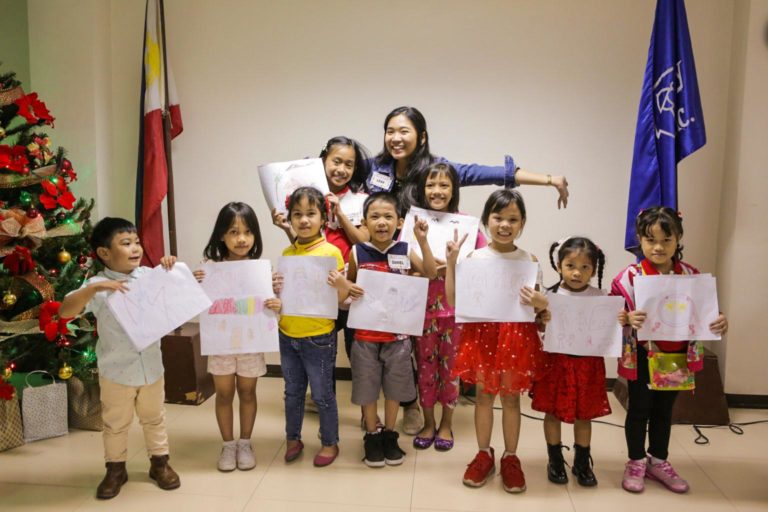 Children in Philippines holding up art in classroom