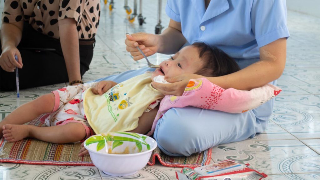 caregiver feeding baby in orphanage