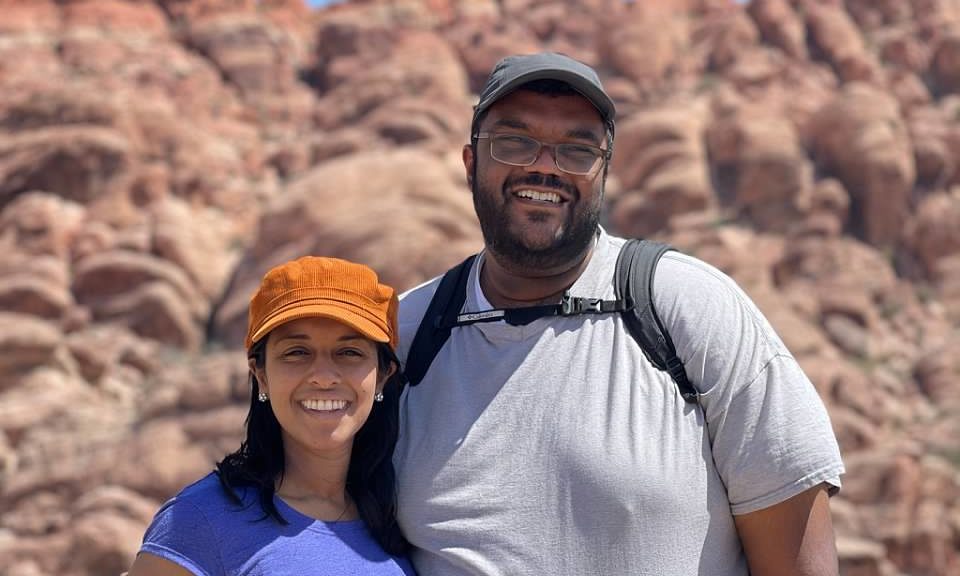 smiling man and woman wearing hiking gear in front of canyons