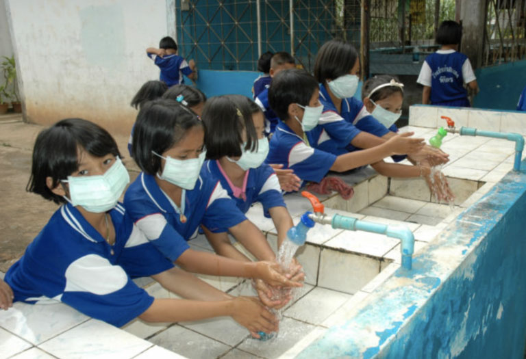Girls washing hands in Covid masks