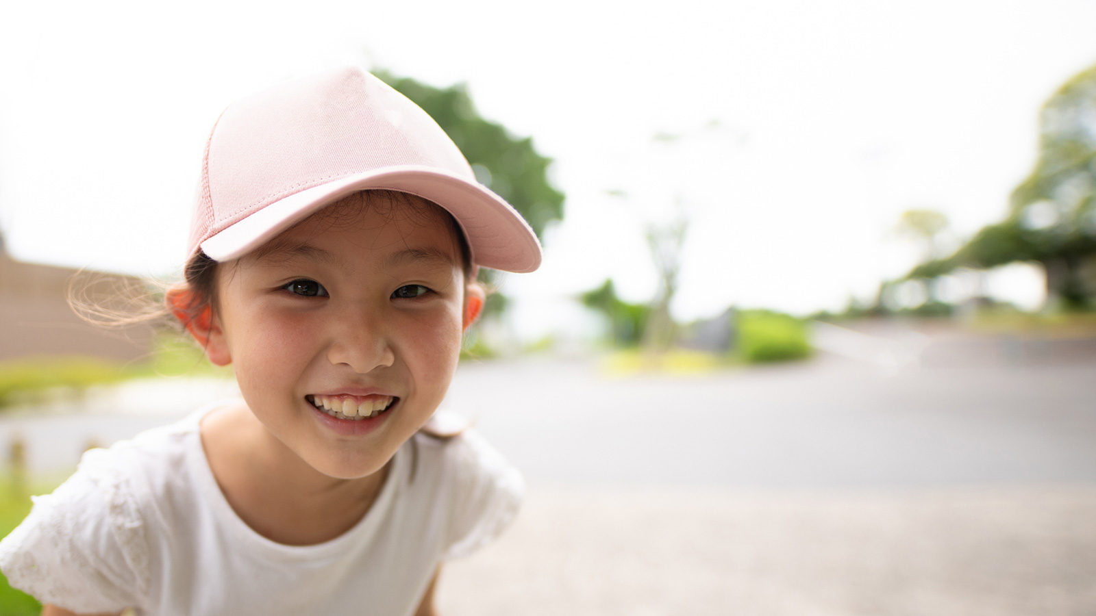 smiling girl wearing light pink baseball hat