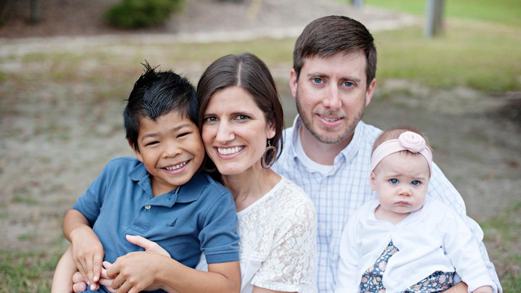 smiling adoptive parents holding son adopted from thailand and baby girl