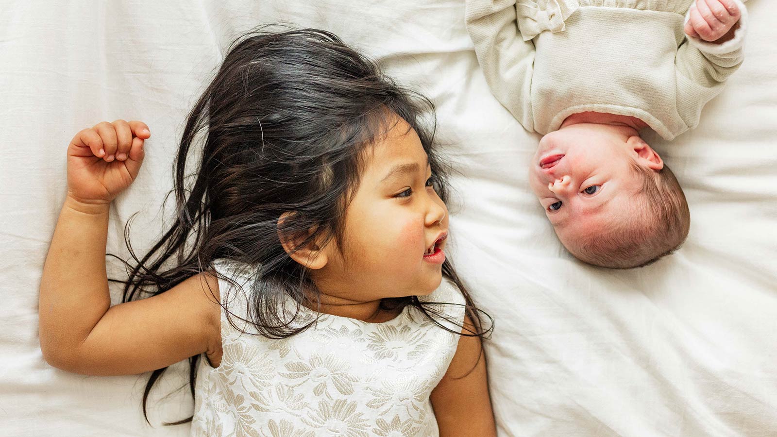 sister adopted from thailand laying next to baby sister