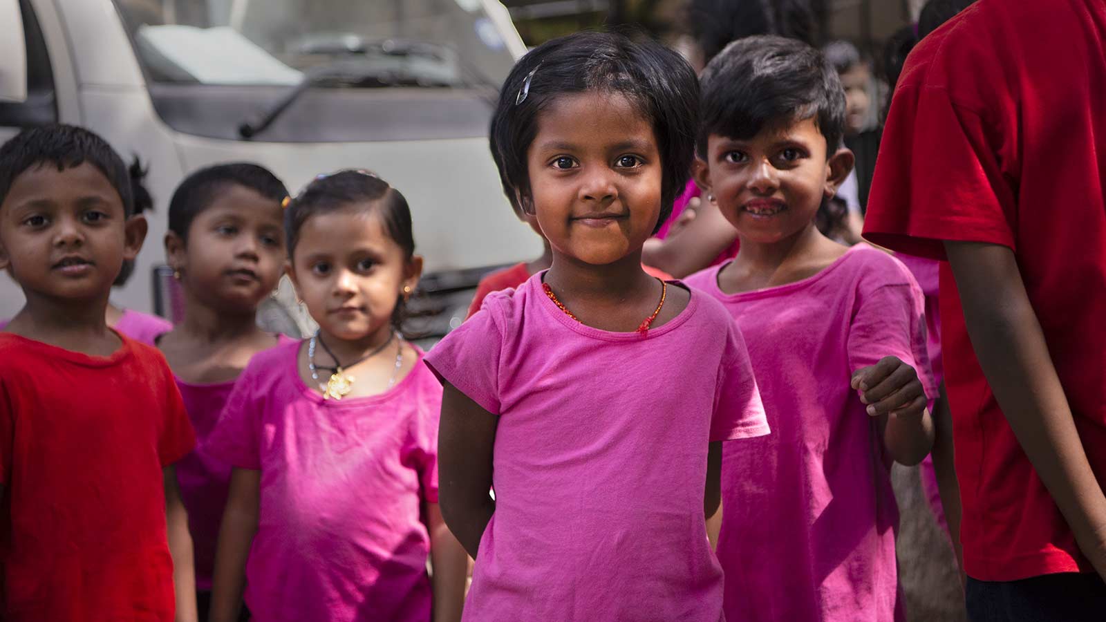 group of sponsored children in india wearing pink and red shirts