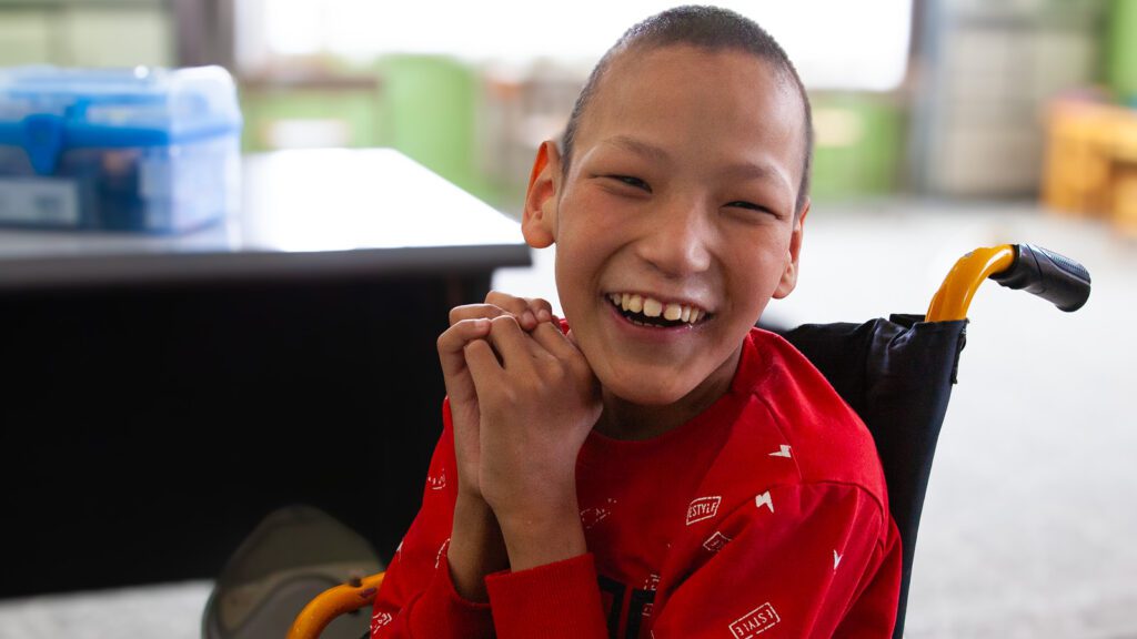 Happy, smiling boy in a wheelchair at school