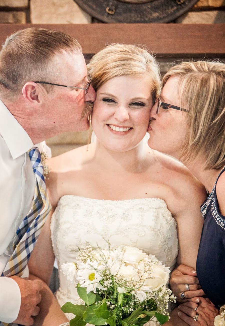 smiling bride receiving a kiss from each parent
