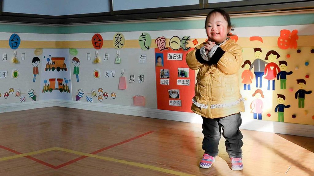 smiling girl with Down syndrome waiting to be adopted