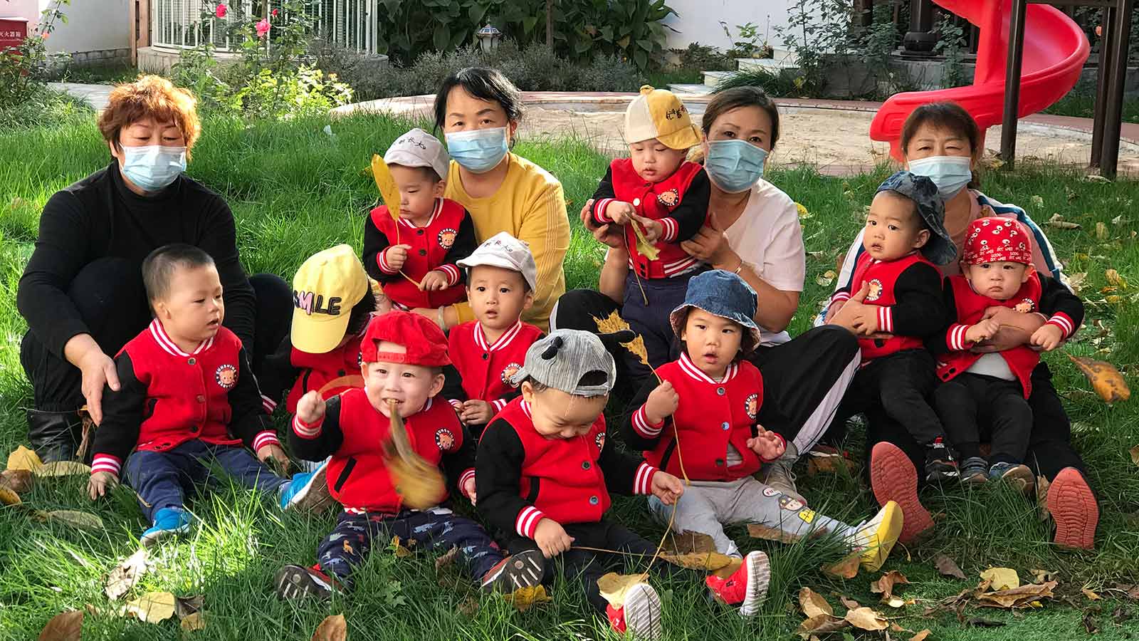 Children on the lawn with caregivers at Peace House medical foster home in China