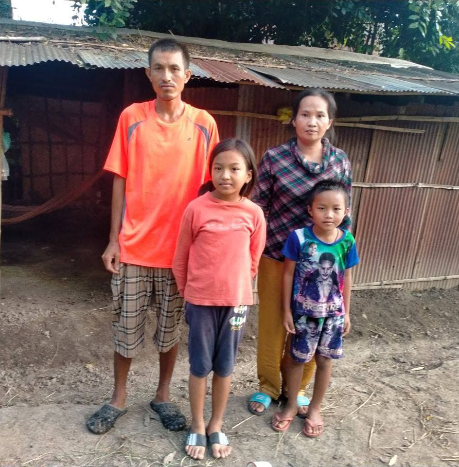 A family in Cambodia stands in front of their house