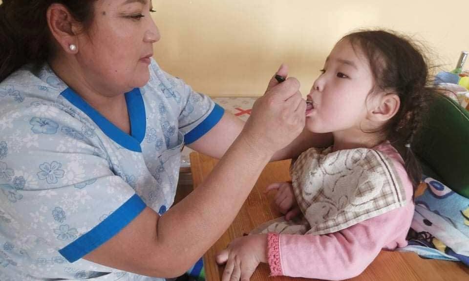 Caregiver feeding a girl with disabilities in Mongolia