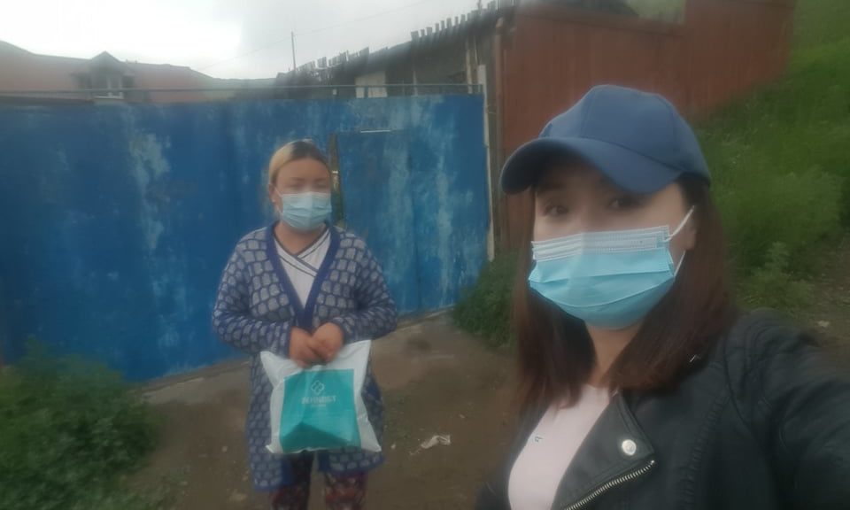 A woman in Mongolia receives a bag of food and medicine from a Holt social worker. 