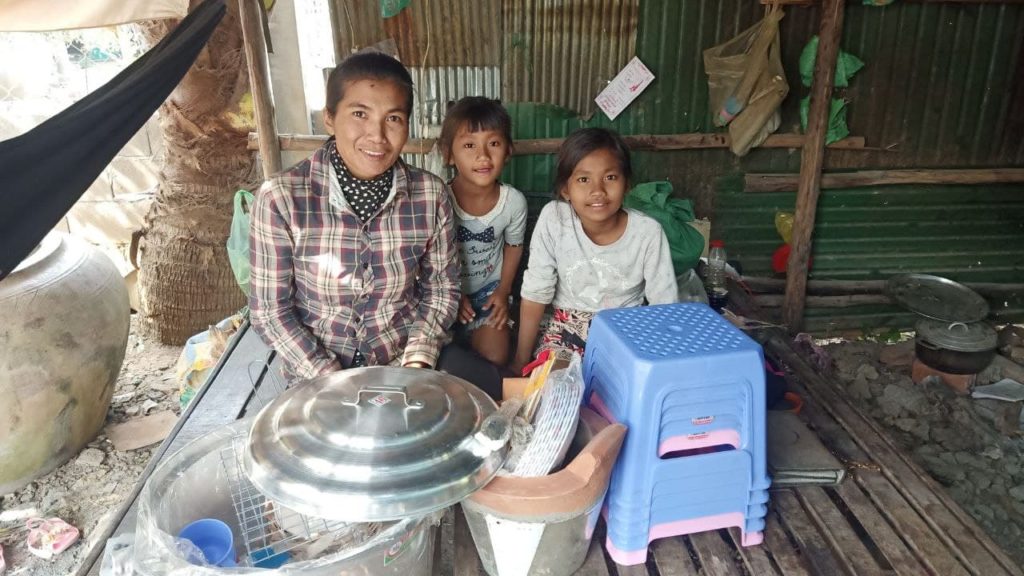 A mom and her two children pose with supplies to start their small business. 