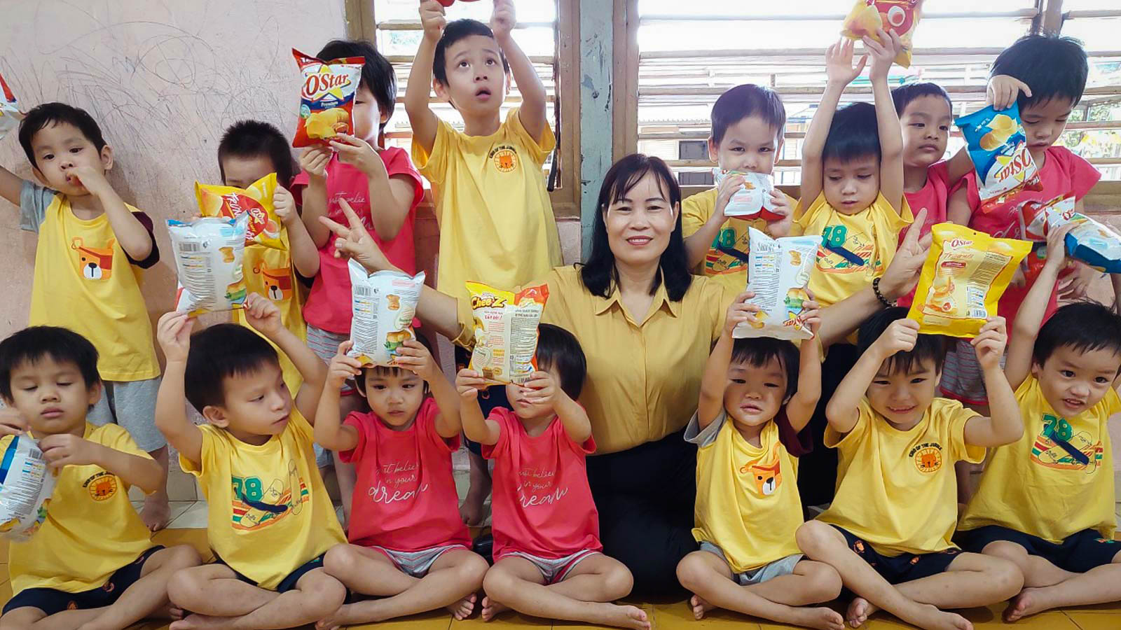 group of children in yellow shirts holding up prizes