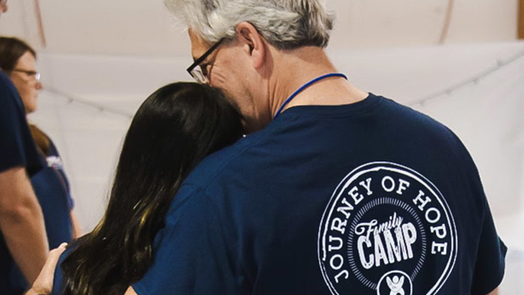 father wearing Journey of Hope TBRI camp shirt with arm around daughter