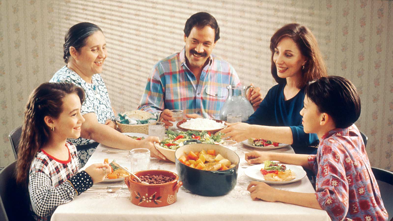 family smiling at each other over the dinner table