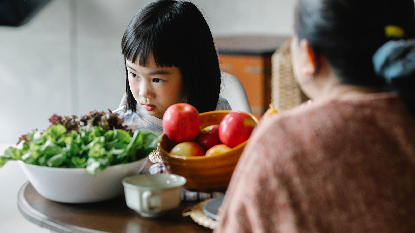 little girl looking away from dinner table