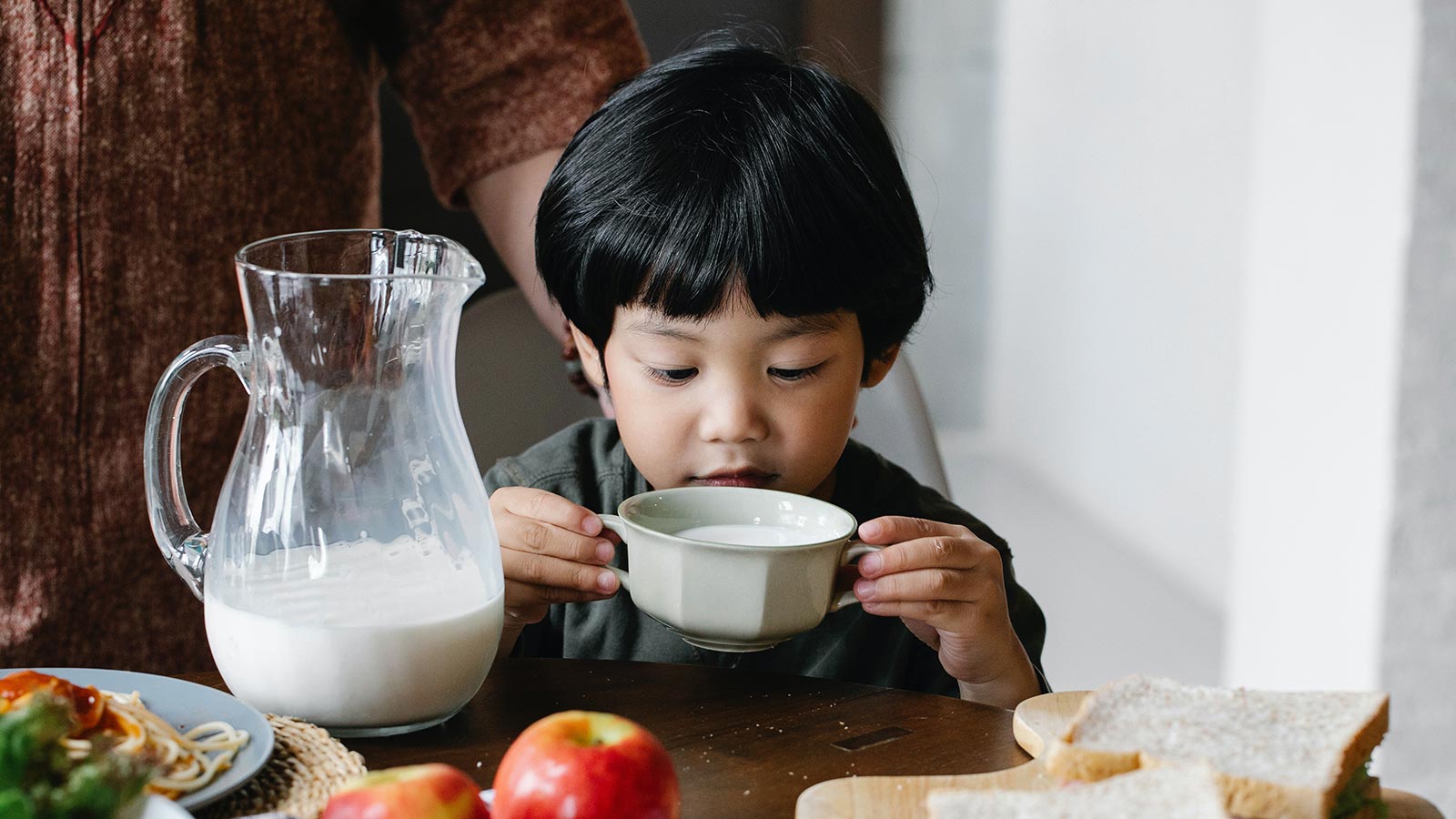 small child drinking milk out of mug