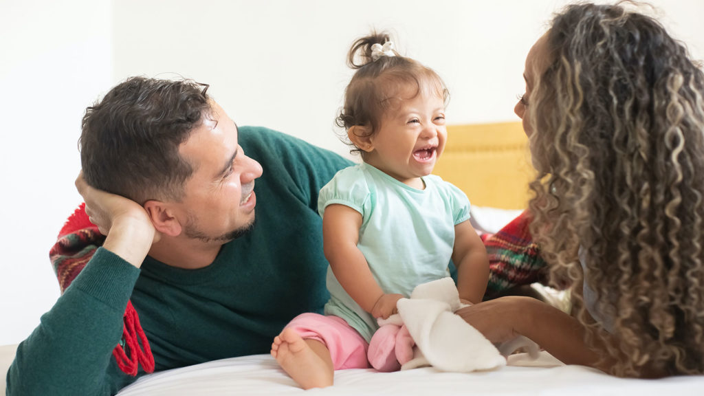 little girl with Down syndrome laughing with parents