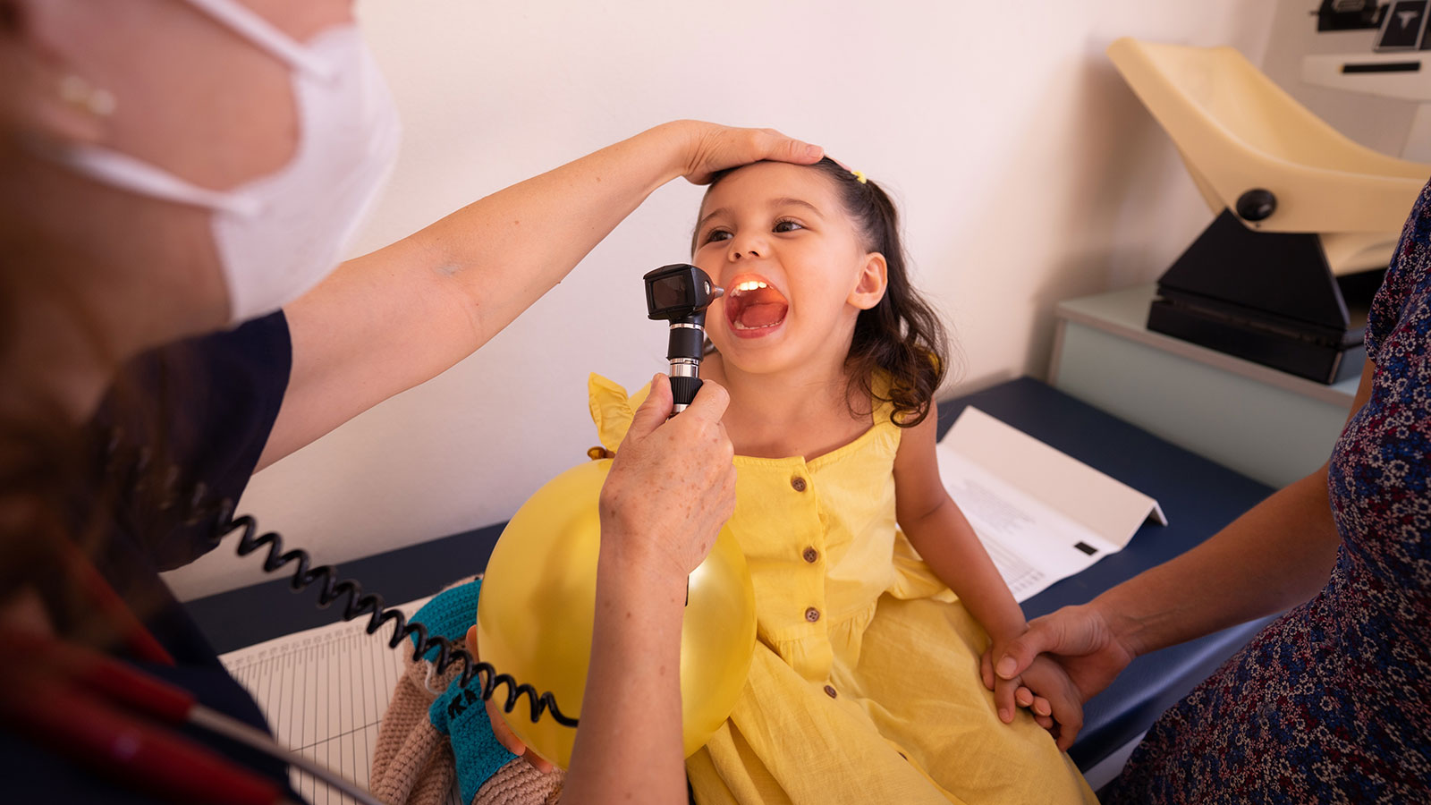 little girl in yellow dress receiving examination at the doctor