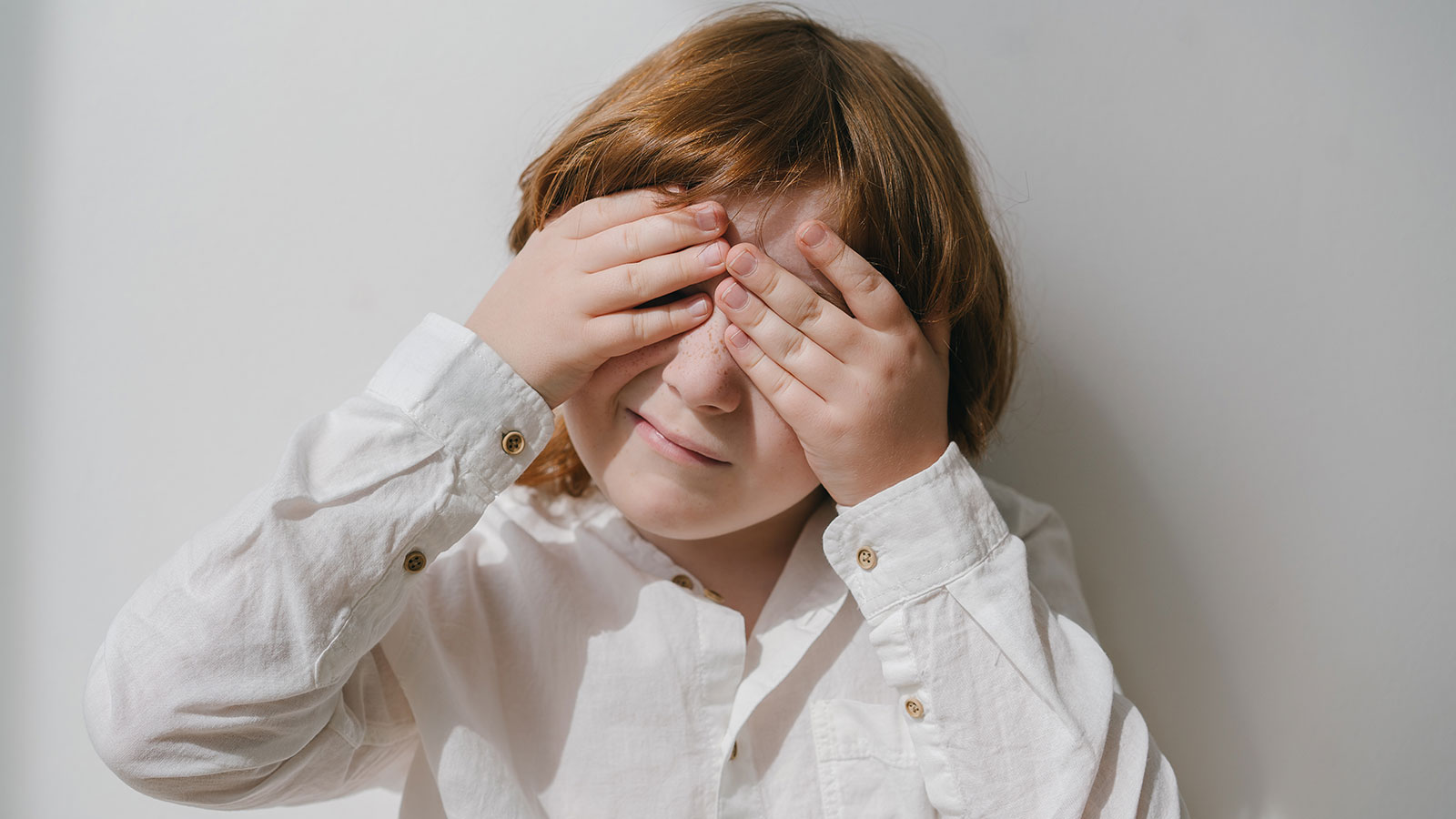 child hiding their face in their hands